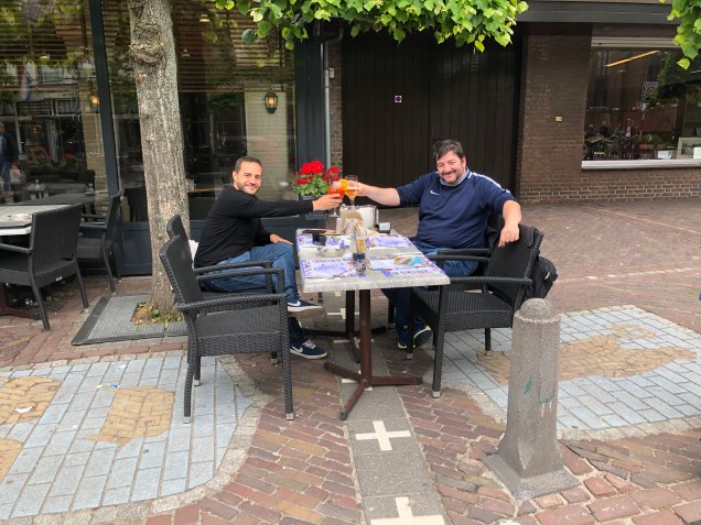 El autor del blog y un amigo brindando en una mesa situada exactamente sobre la frontera entre Bélgica y Holanda